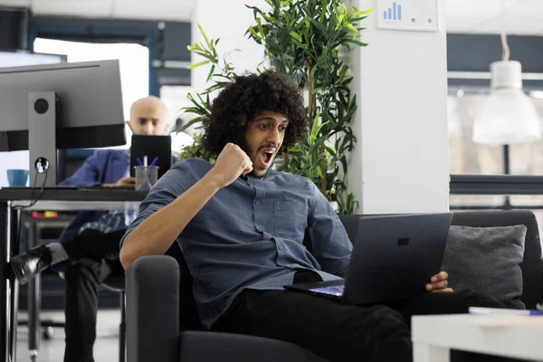 兴奋的阿拉伯企业家在创业办公室为成功的营销活动感到高兴 企业员工在查看笔记本电脑销售报告时表现出得胜的姿态 — 图库照片