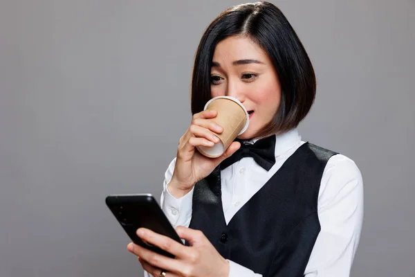 Młoda Azjatycka Recepcjonistka Delektująca Się Kawą Wynos Sprawdzająca Aplikację Smartfona — Zdjęcie stockowe