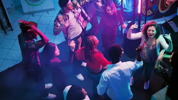 パーティーで踊る若者の群れは ディスコイベントでファンキーな動きを見せています 現代音楽を楽しむ楽しい大人のパーティーが集まり お祝いを楽しんでいます 手持ち撮影 — ストック写真