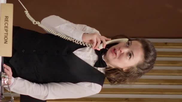 Dikey Videocu Kadın Çalışanı Otel Lobisindeki Sabit Hatlı Telefondan Müşterilerle — Stok video