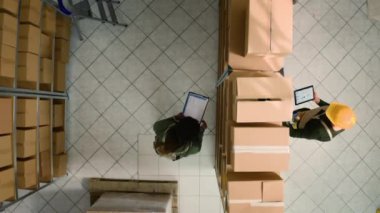 Lojistik koordinatörlerinin ambardaki kusurları karton kutularda incelerken en alttaki görüntüsü. Depo çalışanları stokların ve envanterlerin iyi organize edildiğinden emin oluyor.