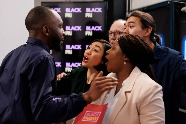 Mad angry diverse people shoppers eager to start Black Friday shopping, arguing with security guy, asking him to open store. Customers tired of waiting in line during seasonal sales