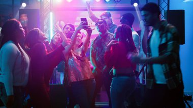 Arkadaşlar disko partisinde fotoğraf çekiyorlar ve geceleri birlikte eğleniyorlar, dans ediyorlar. Bir grup insan telefonda fotoğraf çekiyor, sosyal kutlamalarda eğlenceli anılar yaratıyorlar. El kamerasıyla..