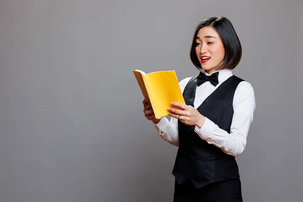 Focalizzato Sorridente Donna Asiatica Receptionist Tenendo Libro Con Copertina Gialla — Foto Stock