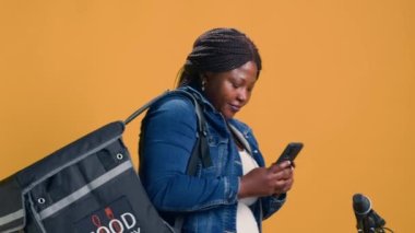 Yemek servisine gitmeden önce hevesli bir teslimatçı kadın iş arkadaşlarına mesaj göndermek için akıllı telefonunu kullanır. Afro-Amerikan kurye talep üzerine paket teslimatı için mobil bir uygulama tarıyor.