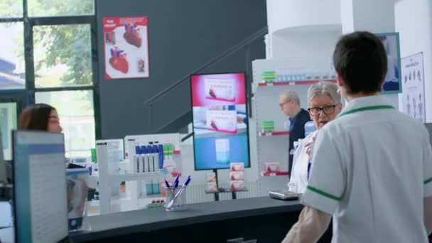 Азиатский Клиент Аптеке Показывает Аптекарю Прописанные Лекарства Сердца Спрашивает Необходимой — стоковое видео