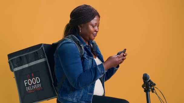 Африканская Американка Исследует Мобильный Телефон Находясь Велосипеде Готовясь Доставке Еды — стоковое видео