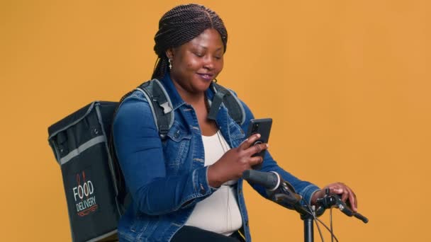 Активна Чорна Жінка Доставляє Їжу Велосипеді Мобільним Телефоном Руці Додаток — стокове відео