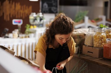 Çevreye duyarlı sıfır atık mağazasındaki kadın yüksek besin değeri olan yiyecekler almakla ilgileniyor. Müşteri alışveriş sepetini yerel bakkalda ücretsiz ürünlerle dolduruyor