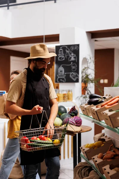無駄なスーパーマーケットのヒップスターは 健康的な地元の野菜でショッピングバスケットを満たしています 環境に配慮した顧客が地元の店から有機非遺伝子組み換え食品を購入 — ストック写真