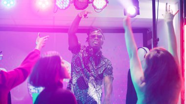 Afrika kökenli Amerikalı DJ 'in gece kulübünde sesi karıştırması, havalı adamın dans pistinde bir grup insanla parti yapması. Panel istasyonunda elektronik karıştırma sesleri çıkaran tuhaf yetişkinler, kulüpler. Üçayak atışı.