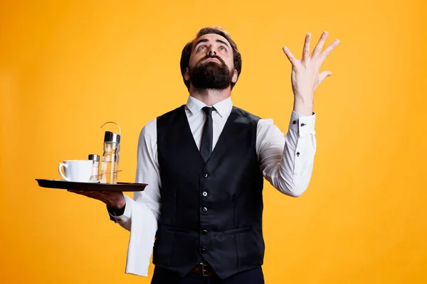 Employee praying to jesus for luck, asking for good fortune and being faithful. Spiritual religious skilled man working as waiter with food platter and formal clothes, feeling optimistic on camera.