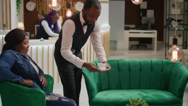 ホテルのロビーでコーヒーを飲む女性は バーサービスからドリンクを購入するクレジットカードを使用しています アフリカ系アメリカ人旅行者が休日に部屋に登録するのを待っている間にポーズを支払う — ストック動画