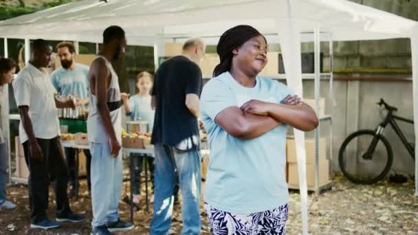 熱狂的な黒人女性ボランティアは 慈善団体の食糧配給イベントで人道援助を提供する準備ができています 多民族慈善団体の従業員が ホームレスの人々に無料の食料を配達している サイドビュー 肖像画 — ストック動画
