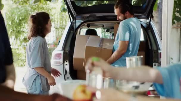 Matresan Ger Den Manliga Volontären Donationslådor Från Bilen Till Behövande — Stockvideo