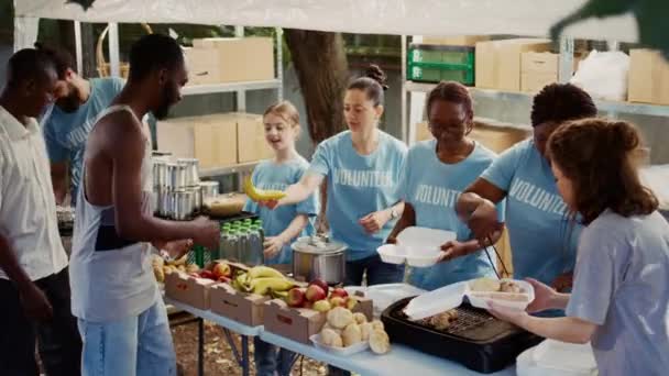 多族裔自愿人员分发捐赠食品 向无家可归者和饥饿者伸出援手 年轻的志愿者与那些不太幸运的人分享新鲜的 免费的食物 — 图库视频影像
