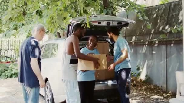 通过提供基本的非易腐产品来帮助饥饿和弱势群体的慈善组织 向当地中心无家可归者提供捐赠箱的男女志愿者 — 图库视频影像