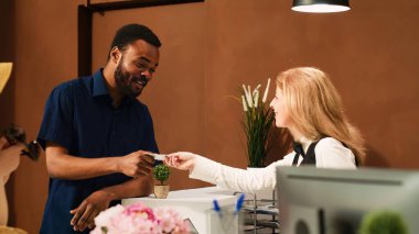 Konuk, resepsiyondan anahtar kartını alıyor. Tropikal otele vardığında konaklama izni alıyor. Resepsiyon lobisinde erkek turist kontrolü devam ediyor. El kamerasıyla..