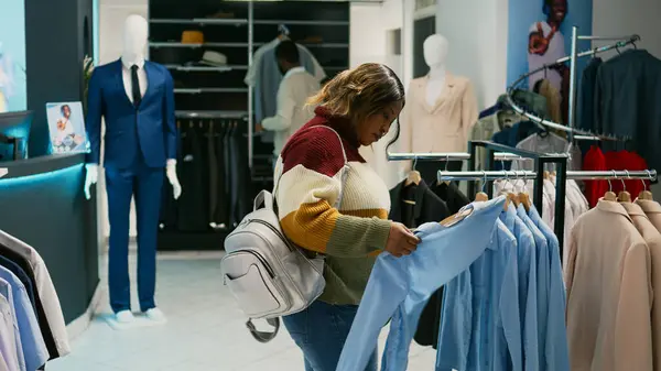 ハンガーで流行の服を検討する若い女性は 衣料品店で正式なまたはカジュアルな服を購入しようとしています ショッピングセンターモールで新しい商品をチェックショッピング大人 商業活動 — ストック写真