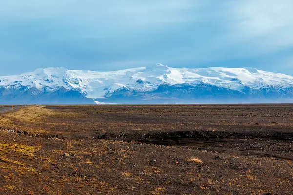 アイスランド地方の豪華なハイランドビューは 雪が山々を覆い 遠くの凍った牧草地を眺めています アイスランドの丘やフィールドの北の風景と道端の美しい道路 — ストック写真