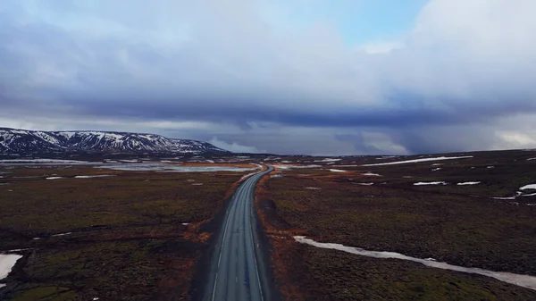 雪山与冰原结冰的田野之间的大路 无人驾驶飞机拍摄的冰山一角 风景优美 斯堪的纳维亚风景线 有山丘 冬季风景 — 图库照片
