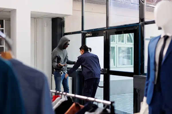 Asian manager catch robber at boutique door in shopping centre, employee asking thief to give back the stolen clothes. African american man stealing fashionable accessories. Burglary concept