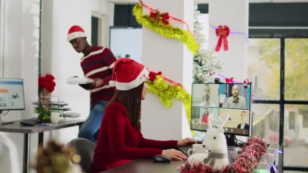 圣诞节期间 在装饰过节日的办公室里 亚洲员工与同事们在网上进行视频交谈 在繁忙的圣诞华丽工作场所 员工使用电脑摄像头与团队进行远程电话会议 — 图库视频影像