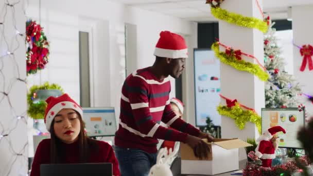 非洲裔美国人在度假前清理办公桌 在装饰过节日的办公室里跳舞 头戴圣诞礼帽的男人外出度假几天 心情很愉快 — 图库视频影像