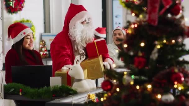 多族裔工人接受同事们的礼物 假装圣诞老人在圣诞装饰办公室里 在寒假期间 穿着服装的员工给公司人员带来了惊喜 — 图库视频影像