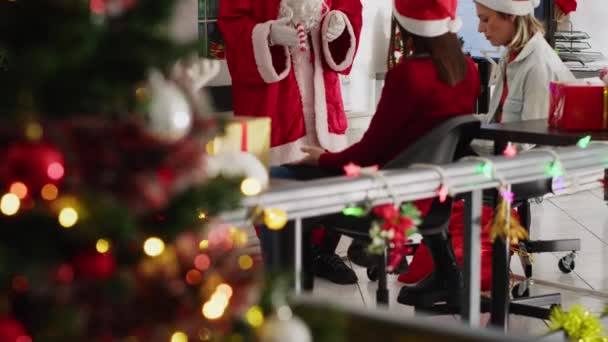 クリスマスシーズンにサンタとして服を着たマネージャーがチームミーティングを開催し デジタル画面で財務収益予測を発表した お祝いのチームリーダー 装飾されたオフィスの動機付けの会社の人員 — ストック動画