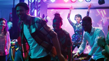 Çeşitli insanlar kulüpte parti veriyor, renkli dans pistinde canlı DJ müziğinin keyfini çıkarıyorlar. Bir grup arkadaş sahne ışıkları ve elektronik seslerle partide eğleniyor, gece kulübünde dans ediyorlar. Üçayak atışı.