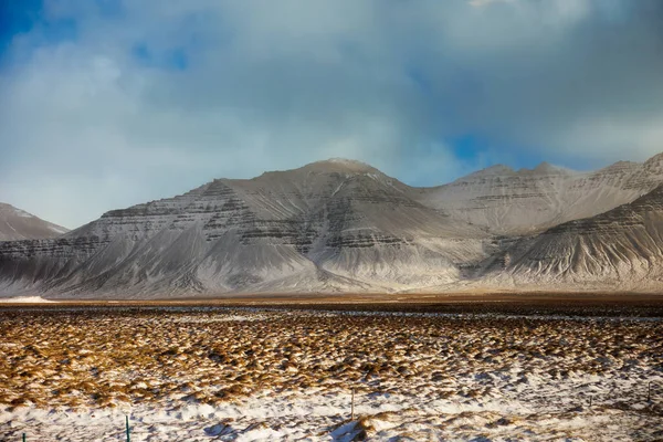 雪の山々や氷山の風景 雪に覆われた美しいノルディックな自然 アイスランドの田舎に沿って巨大な岩の丘と茶色の牧草地 — ストック写真