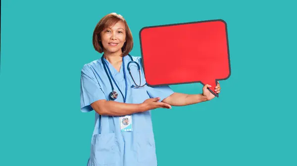 Szczęśliwa Uśmiechnięta Azjatycka Pielęgniarka Trzymająca Czerwony Znak Bańki Mowy Pustej — Zdjęcie stockowe
