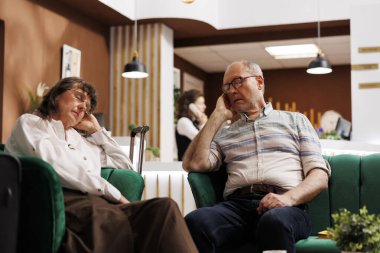 Yorgun yaşlı turistler tatilleri sırasında dinlenme odasındaki rahat bir kanepede dinlenirler. Yaşlı adam ve kadın özel otel resepsiyonunda huzurlu bir şekerleme yapıyorlar..