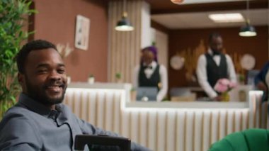 Otelin misafiri giriş yapmak için lobide bekliyor. Bavulun yanındaki resepsiyonda oturuyor ve odayı görmeye hazırlanıyor. Afrika kökenli Amerikalı bir adam tatilde, beş yıldızlı bir tatil yerine varıyor..