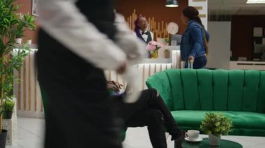 Misafir lobide web sayfasına bakıyor, kayıt yaptırmadan önce otel odasının dinlenme odasında dizüstü bilgisayar kullanarak bekliyor. Afrika kökenli Amerikalı bir adam taşınabilir bilgisayar kullanarak tatil merkezine geliyor..