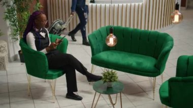 Hızlı kayıt işlemleri ve konaklama süreçlerini hızlandırmak için, resepsiyonist otel odası rezervasyonlu turist indeksine bakıyor. Afrikalı Amerikan personeli.