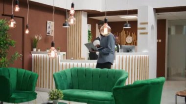 Gezgin oteldeki sosyal medyayı tarıyor, kontrol kağıtlarını imzalamadan önce dinlenme odasında dizüstü bilgisayarla dinleniyor. Afrika kökenli Amerikalı tatilde bilgisayarla tatil yerine geliyor..