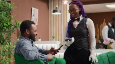 Kişi lüks otelin resepsiyonunda bir fincan espresso almak için NFC ödemesi yapar. Becerikli bir çalışan, büyük hizmetleri için müşterilerinden övgü alır. Lobide içecek servisi yaparlar. El kamerasıyla..