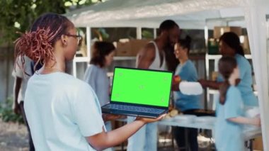 Hayır kurumunda çalışan Afrikalı Amerikalı bir kadına elinde boş kromakey şablonu olan bir laptop gösteriliyor. Özelleştirme için izole edilmiş yeşil ekranlı kablosuz bilgisayarı kullanan genç siyahi bayan..