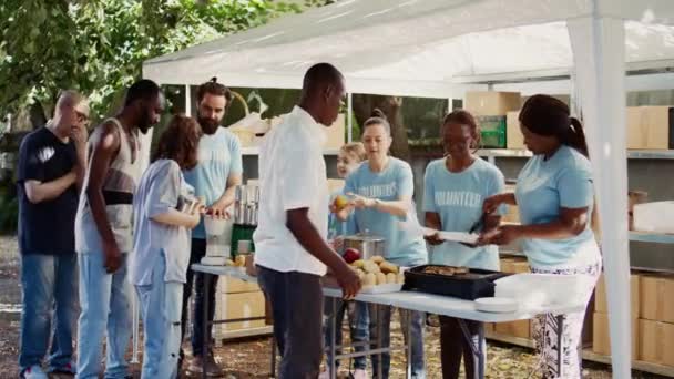 许多背景的人聚集在外面 分发不易腐坏的捐款 帮助穷人和无家可归者 多种族志愿者为有需要的个人提供免费的 新准备的食物 — 图库视频影像