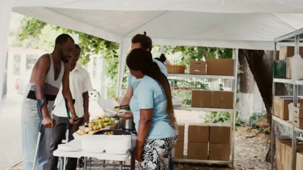 Жінка Афроамериканка Доброволець Допомагає Чоловікові Милицях Його Їжею Основними Речами — стокове відео
