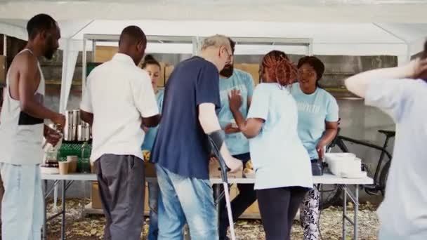 在人道主义食品促销活动中 一个拿着拐杖的白人老人得到了一位善良黑人妇女的帮助 青年志愿者向穷人 无家可归者和残疾人提供人道主义救济 手持射击 — 图库视频影像