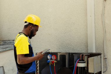 Afrika kökenli Amerikalı uzman, açık hava havalandırma kanallarından gelen sıcak hava şikayetleri üzerine görevlendirildi. Nitelikli elektrikçi, tam sorunları tespit etmek için profesyonel manifolt ölçer kullanıyor