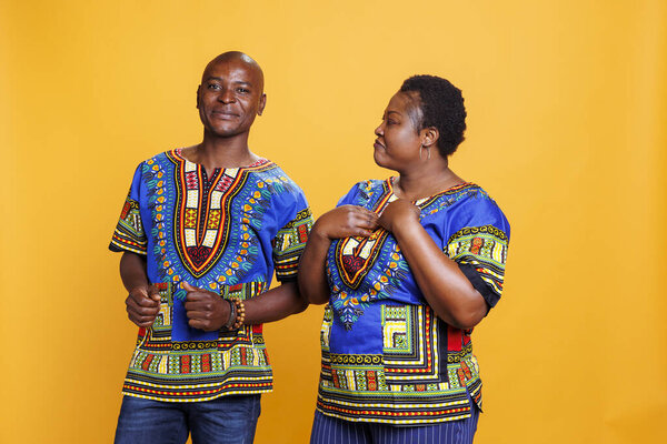 Mid adult woman looking at husband with affection emotion. Cheerful man and woman in relationship showing bonding, love and happiness while posing together in studio portrait