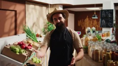Sahibi ilk müşterileri vegan biyo-sıfır atık süpermarket açılışında karşılıyor, kırmızı kurdeleyi kaldırıyor. Girişimci, yerel bakkal dükkanında etik kaynaklı alışveriş yapanları karşıladı.