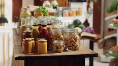 Sıfır atık süpermarketi tarafından kullanılan geri dönüştürülebilir cam kaplarda bulunan toplu ürünler, işlevlerindeki tek kullanımlık plastikleri ortadan kaldırıyor. Sürdürülebilir ambalajda yerel kiler zımbaları