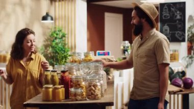 Yaşlılar tarafından işletilen sürdürülebilir sıfır atık süpermarketinin müşterilere yardım etmesi. Civardaki dükkan, organik ürünler için alışveriş yapan müşterilerle dolu.