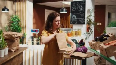 Sıfır atık süpermarketindeki kadın, zararsız sebze alırken kirletici olmayan kağıt torba kullanıyor. Düşük karbondioksit emisyonlu ve tek kullanımlık plastik politikası olmayan yerel bir dükkanda çalışan
