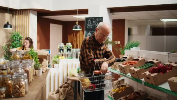 面带微笑的年长客户在零废物超市货架上寻找厨房主食的肖像 快乐的老年人在当地杂货店的可重复使用的罐子里购买有机食品 — 图库视频影像